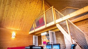 A wooden interior with a dining area, red sofa, and a staircase. - Safari.... (Le Vigen)