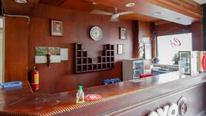 Una zona de recepción con mostrador de madera, cuadros en la pared, un reloj y un extintor.