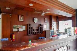 Una zona de recepción con mostrador de madera, cuadros en la pared, un reloj y un extintor.