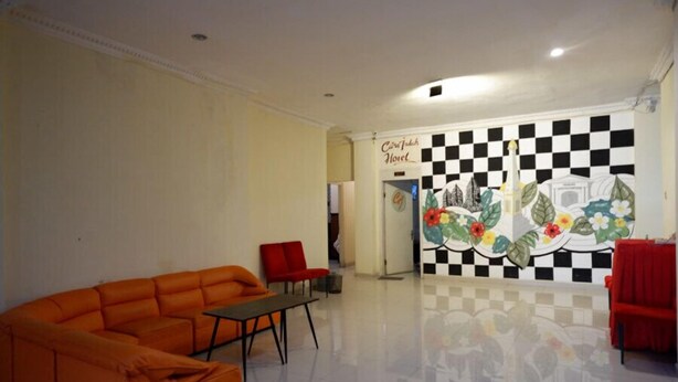 Eine Hotellobby mit Wandgemälde in Schachbrettoptik, einem großen orangefarbenen Sofa und einem roten Sessel.