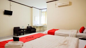 Ein Hotelzimmer mit zwei Betten, einem Schreibtisch, einem Stuhl, einem Fernseher und einer Klimaanlage.