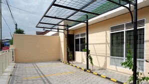 Un espacio al aire libre techado con piso de baldosas, líneas de estacionamiento amarillas y una estructura de techo de vidrio.