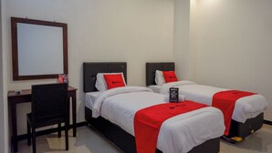 A hotel room with two beds, each with a red blanket and white bedding. There is a desk with a chair and a mirror on the wall. - Reddoorz @ Jalan Wonosari Km.9 (Yogyakarta)