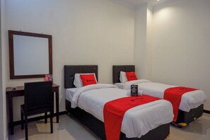A hotel room with two beds, each with a red blanket and white bedding. There is a desk with a chair and a mirror on the wall. - Reddoorz @ Jalan Wonosari Km.9 (Yogyakarta)