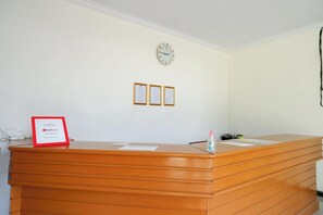 A reception desk with a clock, framed certificates, and a sign indicating a partnership with RedDoor's. - Reddoorz @ Jalan Wonosari Km.9 (Yogyakarta)