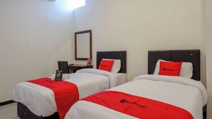 Two twin beds with red and white bedding, a small table with a lamp, and a mirror on the wall. - Reddoorz @ Jalan Wonosari Km.9 (Yogyakarta)