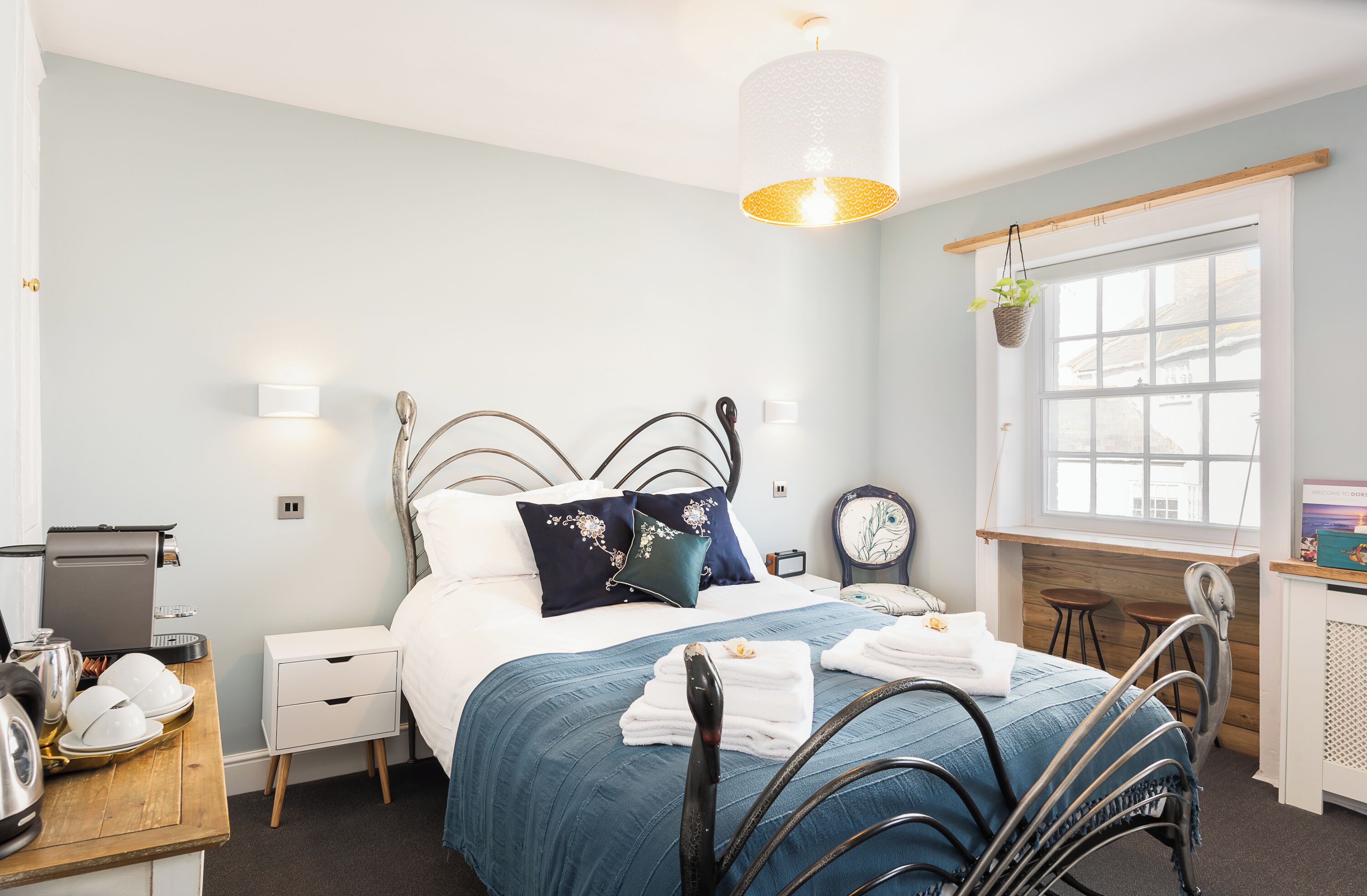 A neatly arranged bedroom with a bed, bedside table, lamp, and a window with a view.