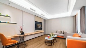 Un salon moderne avec un canapé, une table basse, un téléviseur et un ordinateur portable posé sur une petite table.
