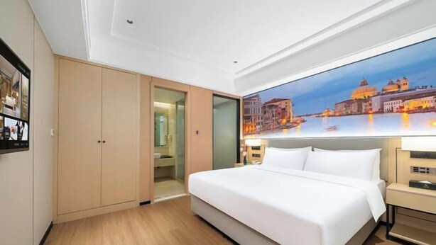 Une chambre d’hôtel avec un grand lit, une armoire, une salle de bain et une vue sur la ville.