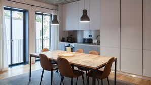 Eine moderne Küche mit Holztisch und -stühlen, Pendelleuchten und Blick ins Freie.