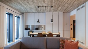 Ein modernes Wohnzimmer mit einer Couch, einem Esstisch und Pendelleuchten.