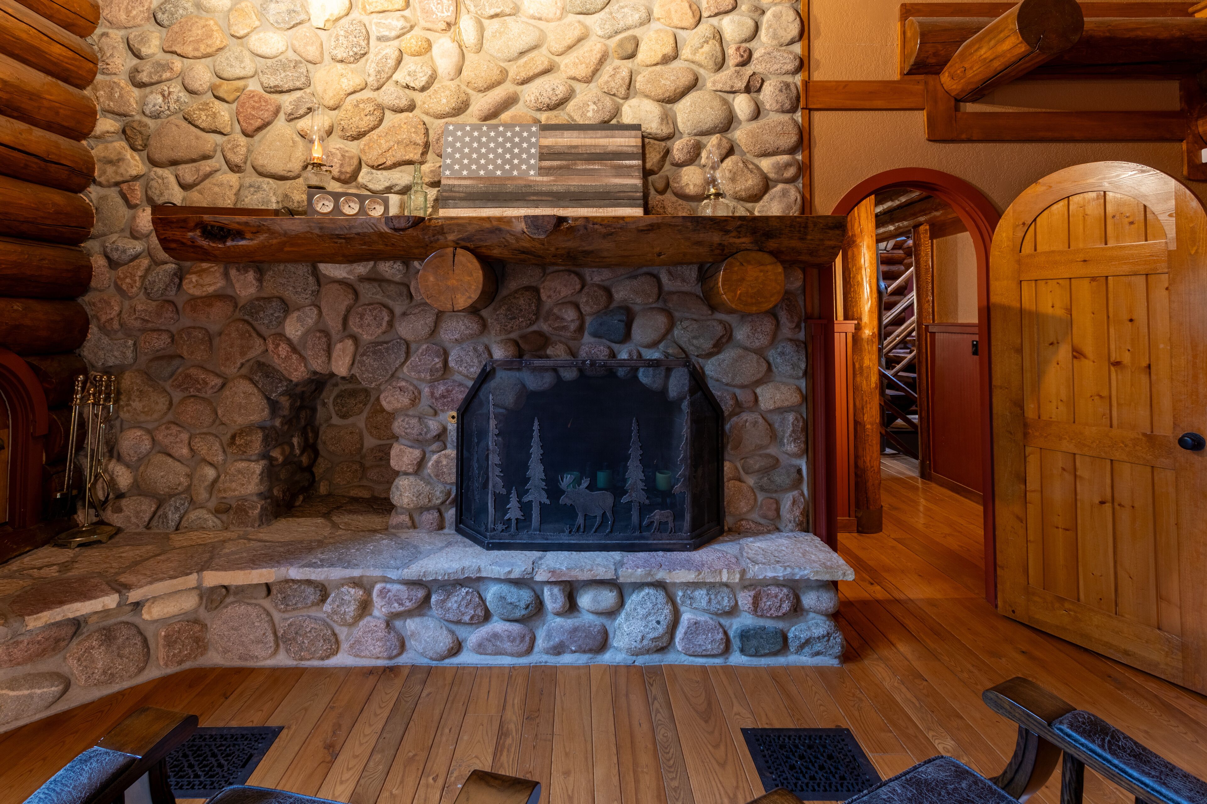 Una chimenea de piedra con repisa de madera, una bandera y un estufa de leña.