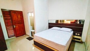 Ein Schlafzimmer mit einem Bett, einem Holzschrank, einem Spiegel und einem kleinen Nachttisch.
