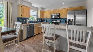 Une cuisine moderne avec des meubles en bois, des appareils en acier inoxydable et une table à manger en verre.