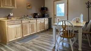 A kitchen with wooden cabinets, a dining table with chairs, a window, and a door.