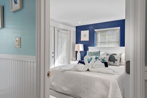 A bedroom with a bed, a nightstand, a lamp, and a window with blinds.