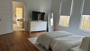 A bedroom with a bed, a TV on a dresser, a window, and a door leading to another room. - Beautiful, historic home - Private (Birmingham)