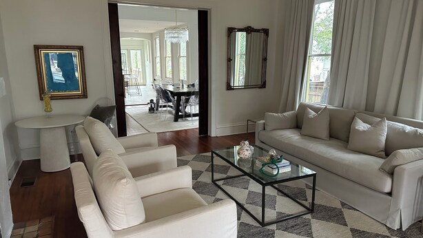 A modern living room with a sofa, armchairs, a glass coffee table, and a dining area visible through an open door. - Beautiful, historic home - Private (Birmingham)