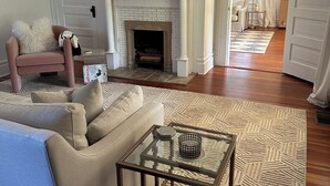 A living room with a fireplace, a sofa, a coffee table, and a patterned rug. - Beautiful, historic home - Private (Birmingham)