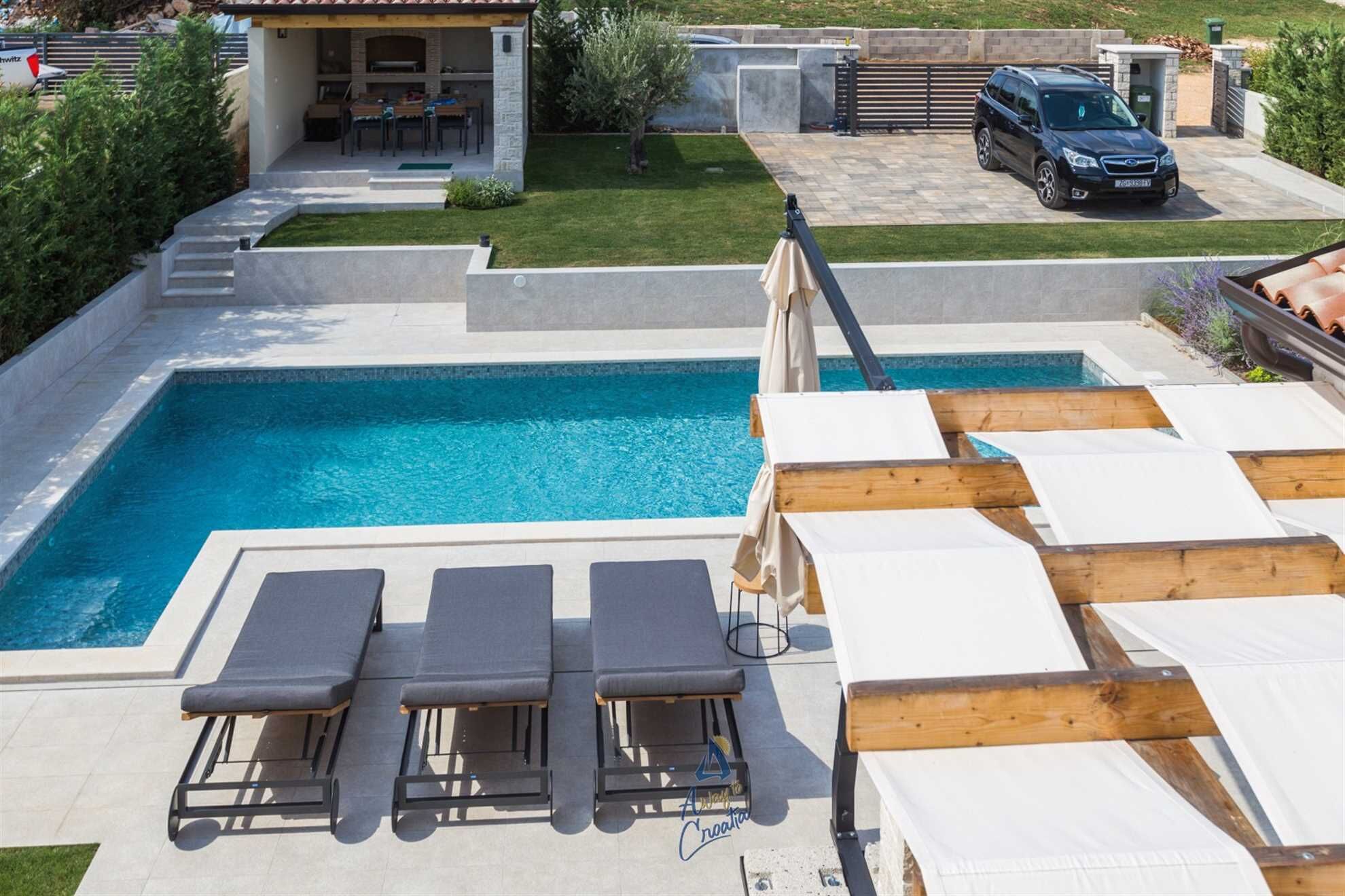 A swimming pool with lounge chairs and a covered patio area.