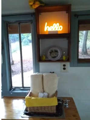 Una habitación con un cartel que dice 'hello', una cesta con toallas y vistas por una puerta.