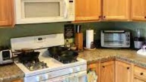 A kitchen with wooden cabinets, a white stove, and two microwaves.