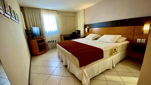 A hotel room with a large bed, a TV, a desk, and a chair. - Acorde com vista mar em Ponta Negra (Natal)