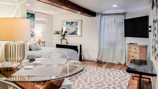 A modern living room with a glass dining table, a sofa, a TV, and a painting on the wall. - Cozy Apartment Minutes from Downtown (Rapid City)