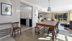 A modern kitchen with a dining area, a coffee machine, and a dining table with chairs. - Surf, Sand & Summer Vibes. (Waiotahe)