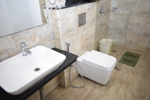A bathroom with a white sink, a toilet, and a shower. - Hotel Million Day (Mayiladuthurai)