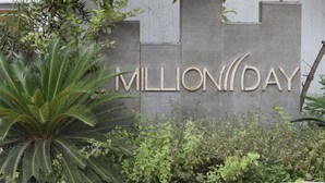 Un letrero con la inscripción “MILLION DAY” en letras grandes, rodeado de follaje.