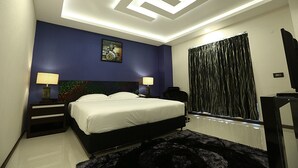 Un dormitorio moderno con una cama, mesitas de noche, un cuadro y una ventana con cortinas.