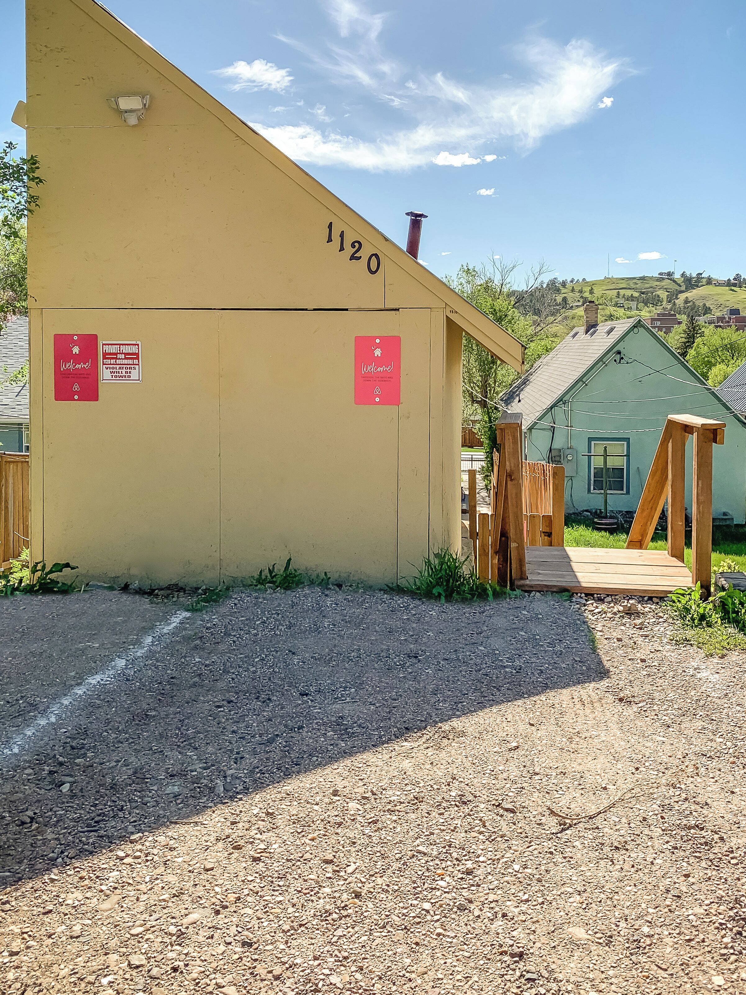 Un bâtiment portant le numéro « 1120 » sur son côté, une structure en bois devant, et un chemin de gravier menant à l’entrée.