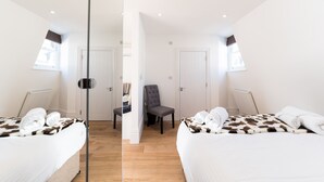 A mirrored room with two beds, a chair, and a window. - Pet-friendly Fulham Broadway Penthouse, Sw Balcony (London)