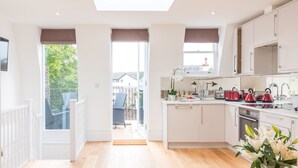 A modern kitchen with white cabinets, a large window, and a view of the outdoors. - Pet-friendly Fulham Broadway Penthouse, Sw Balcony (London)