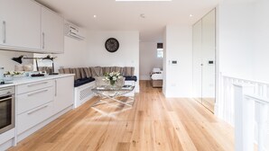 A modern kitchen with white cabinets, a dining area with a glass table, and a living room with a sofa and a coffee table. - Pet-friendly Fulham Broadway Penthouse, Sw Balcony (London)