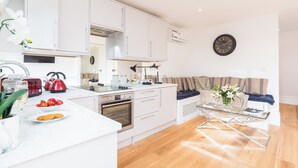 A modern kitchen with white cabinetry, a red kettle, and a glass coffee table. - Pet-friendly Fulham Broadway Penthouse, Sw Balcony (London)