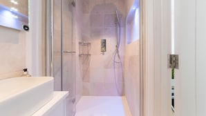 Une salle de bain moderne avec une douche à parois de verre, un lavabo blanc et un miroir.