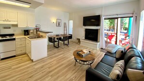 A modern living room with a black leather sofa, a wooden coffee table, and a fireplace.