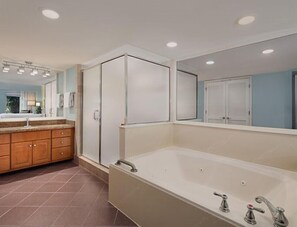 Bathroom features a large bathtub, wooden vanity, and a window with blinds.