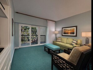 Relax in this stylish living room with a sofa, chair, and artwork, leading to a serene outdoor space with a view.