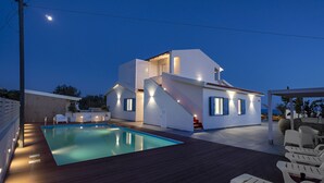 Een modern huis met een zwembad, terras en een trap naar de bovenverdieping.