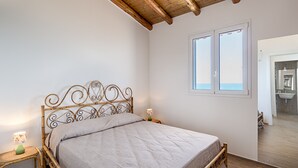 Een slaapkamer met een bed, een raam en een deur naar een badkamer.