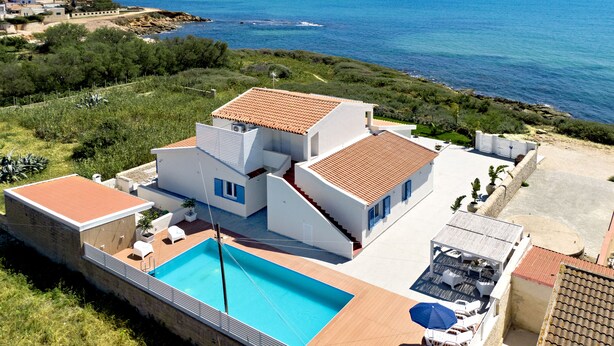 Een moderne villa met een zwembad, meerdere balkons en uitzicht op zee.