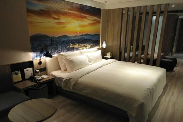 A hotel room with a large bed, a nightstand, a desk, and a round table. - Atour Hotel (Shenzhen)