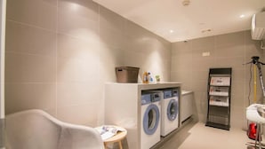 A modern bathroom with a bathtub, a washing machine, and a small table with a towel. - Home Inn Selected (Nanjing)
