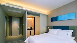 A modern hotel room with a large bed, a desk with a chair, a wardrobe, and a bathroom. - Home Inn Selected (Nanjing)