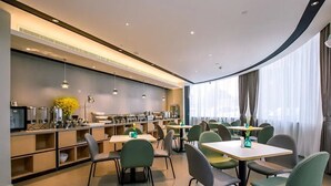 A modern dining area with tables and chairs, a counter with kitchen appliances, and a large window with curtains. - Home Inn Selected (Nanjing)