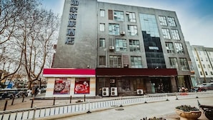 A modern hotel with a prominent sign on the facade, multiple air conditioning units, and a pedestrian walkway in front. - Home Inn Selected (Nanjing)