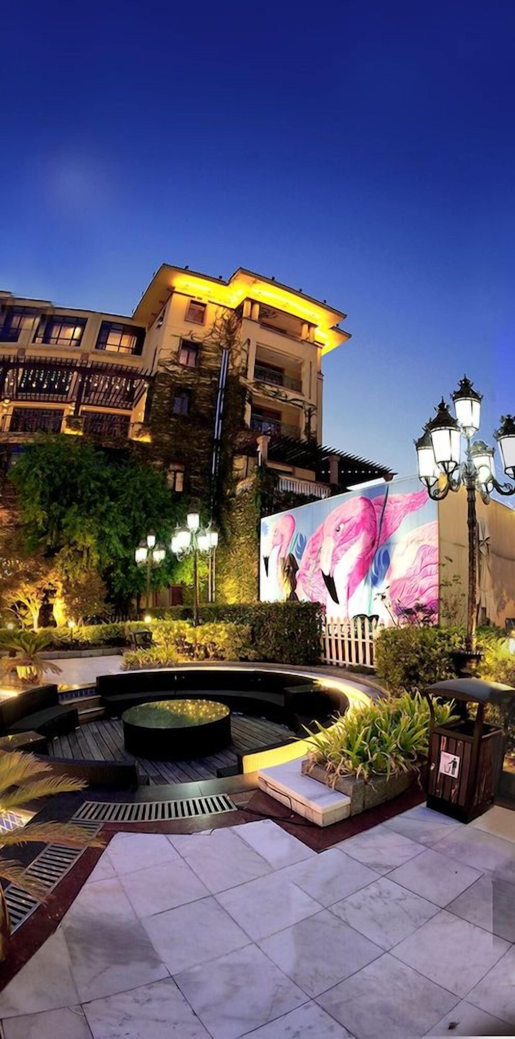 A courtyard with a fountain, seating areas, and a building with a large mural.